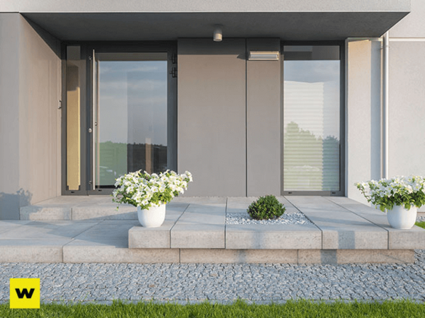 Moderner Hauseingang mit grauen Fliesen, großen Fenstern und weißen Blumentöpfen.